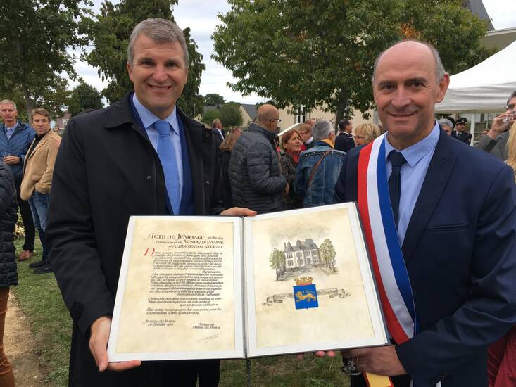 Die beiden Stadtoberhäupter der Städte Remseck am Neckar und Meslay du Maine mit einem Buch in der Hand.