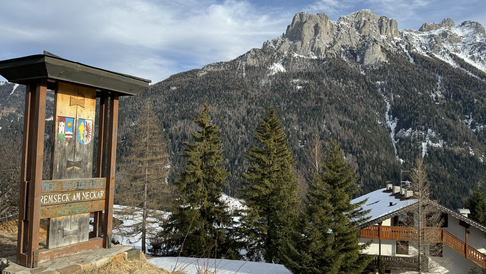 Holztafel mit de Wappen von Remseck am Neckar und San Giovanni di Fassa am Ortseingang in San Giovanni di Fassa.