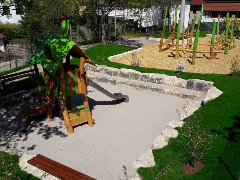 Spielplatz mit Sandkasten, Rutsche und Schakel.