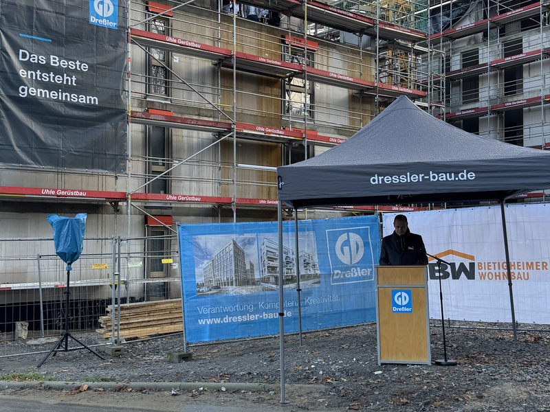 Rede von einer Person vor einem Haus im Rohbau.