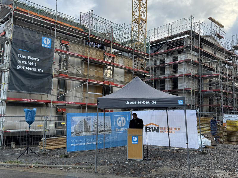 Rede von einer Person vor einem Haus im Rohbau.