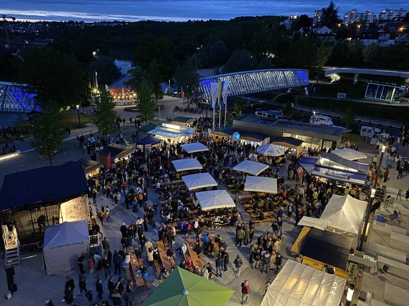 Der Marktplatz von oben bei Dämmerung mit vielen Besuchern. Eine Bühne und einige Stände und Sitzgelegenheiten sind aufgebaut.