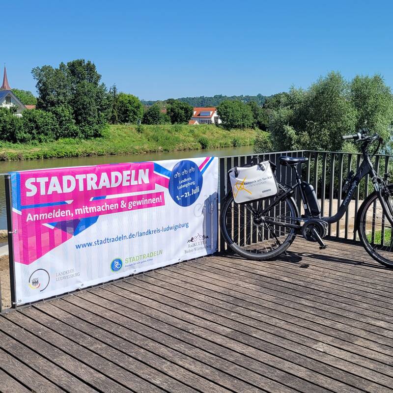 Fahrrad auf dem Balkon zum Neckarstrand, daneben das Plakat zum Stadtradeln.