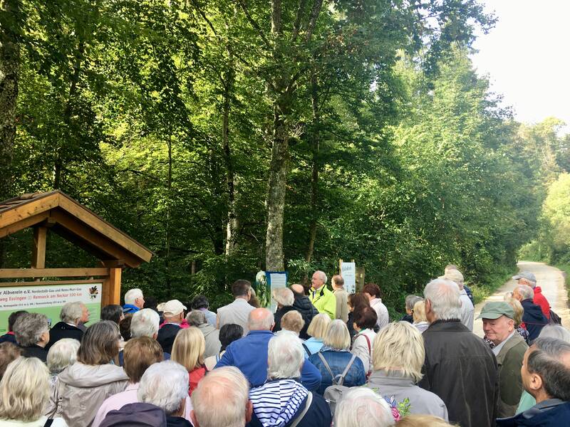 Menschengruppe im Vordergrund, im Hintergrund Wald.