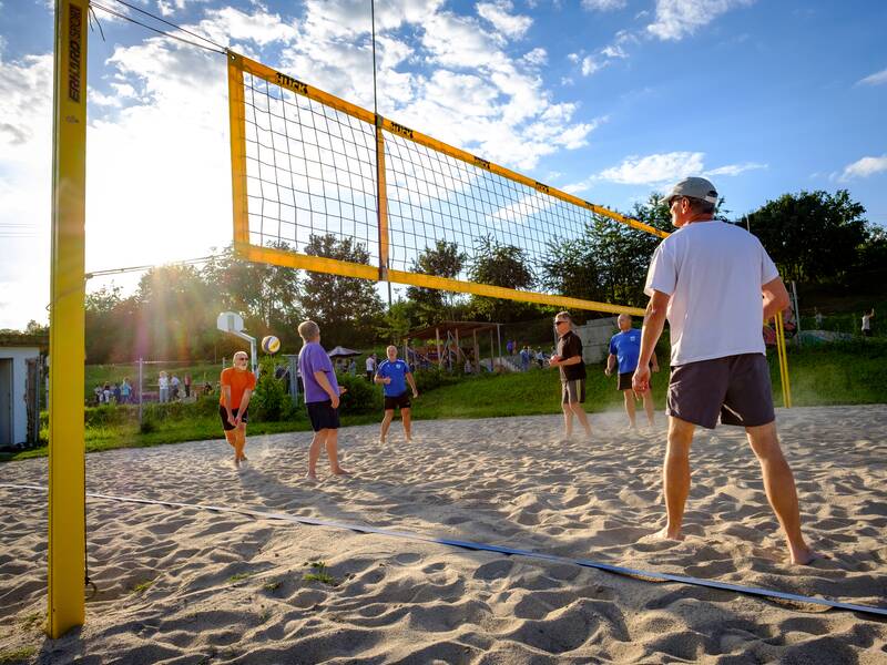 Volleybaldfeld mit Menschen geällt, die Sonne scheint.