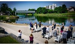 Menschen am NEckarstrand, im Hintergrund fließt der Neckar vorbei und man sieht eine Glasbrücke.